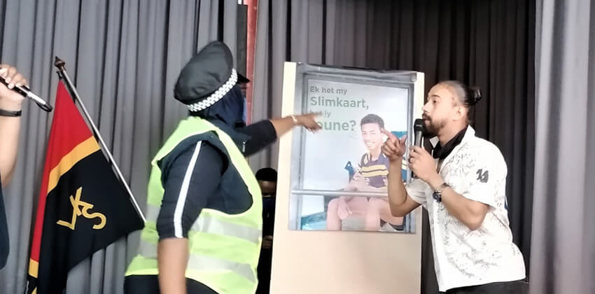 An actor depicting a communication champion scolding an actor depicting a school boy spraying the bus shelter with spray paint.