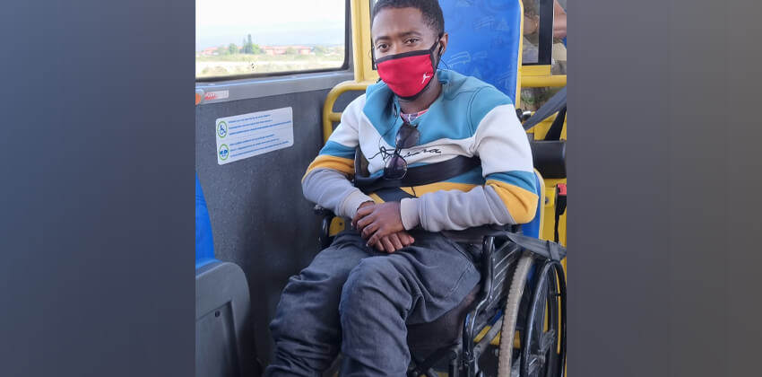 A person sits safely strapped into his wheelchair inside a bus.