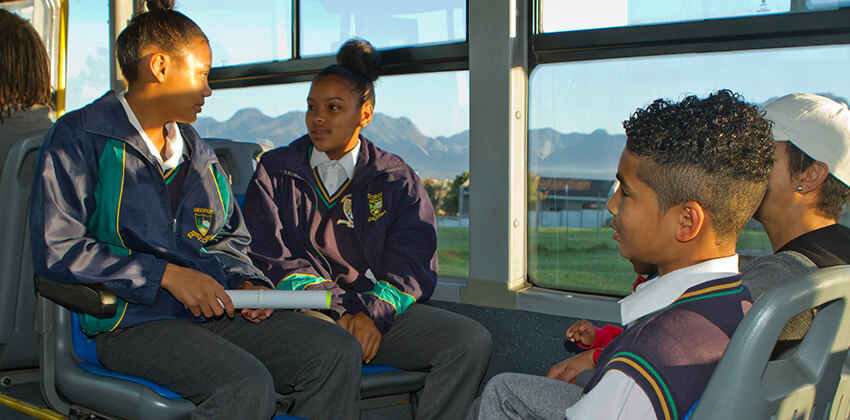 A group of children in school uniform sitting in a bus.