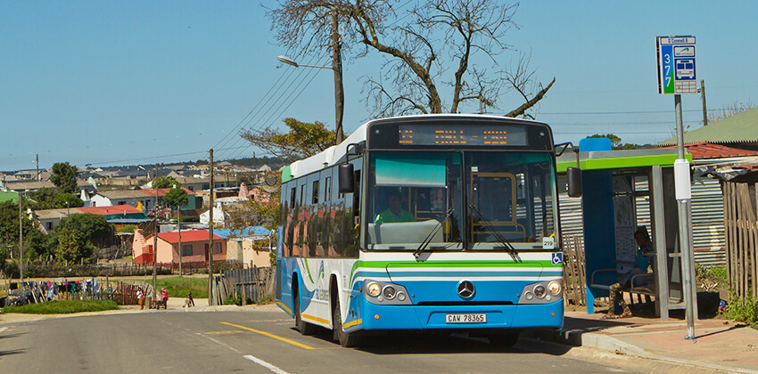 A GO GEORGE bus at a bus stop in a residential area.