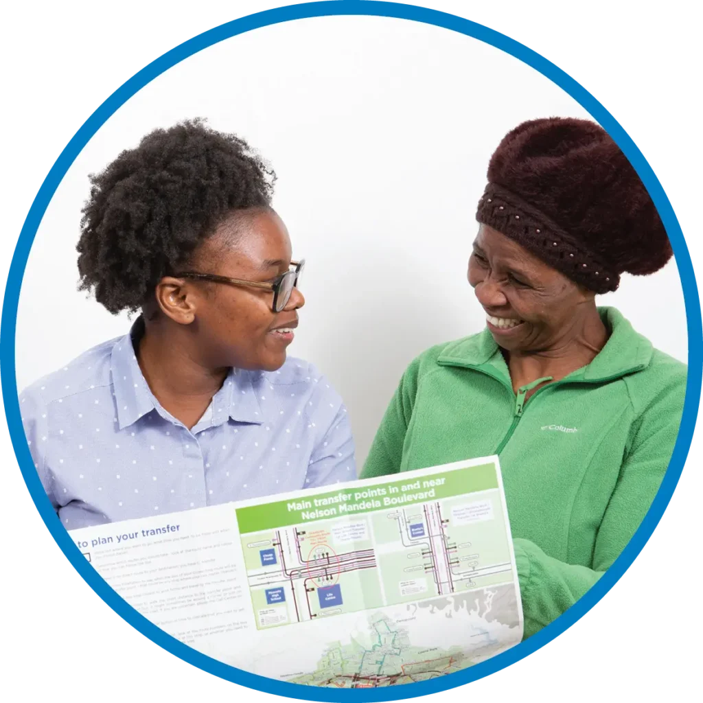 Two women talking and smiling while looking at a printed route map.