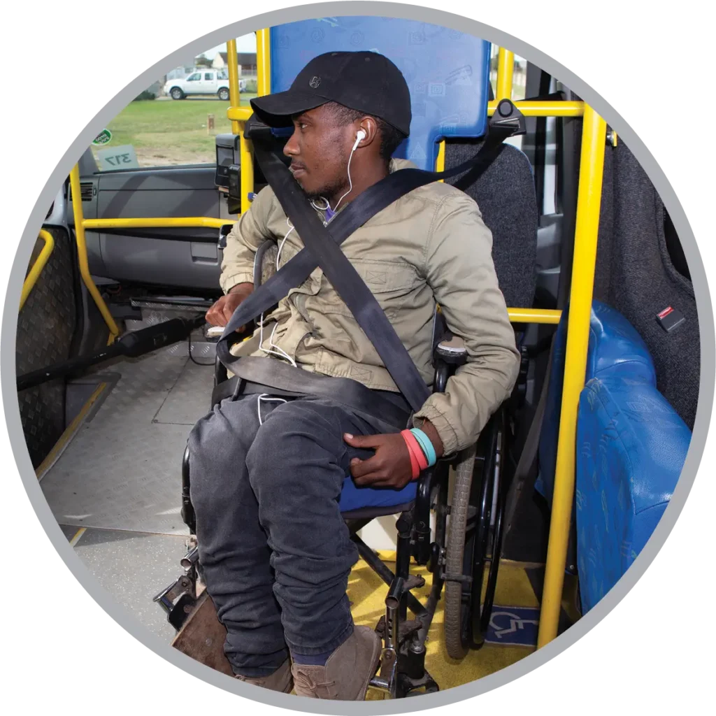 A person in a wheelchair strapped into the wheelchair dock using the safety belts on the bus.